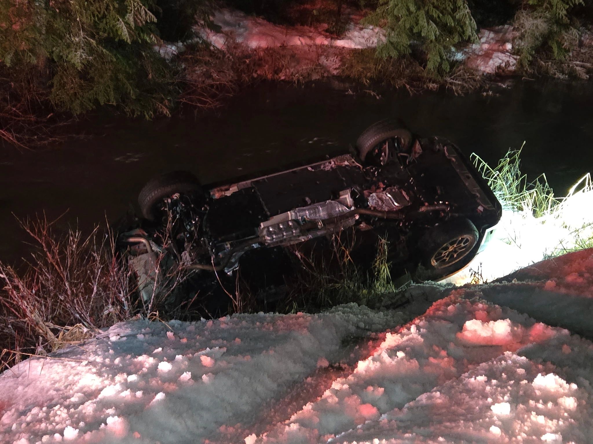 Night-time recovery of a vehicle in a creek lit by truck work-lights